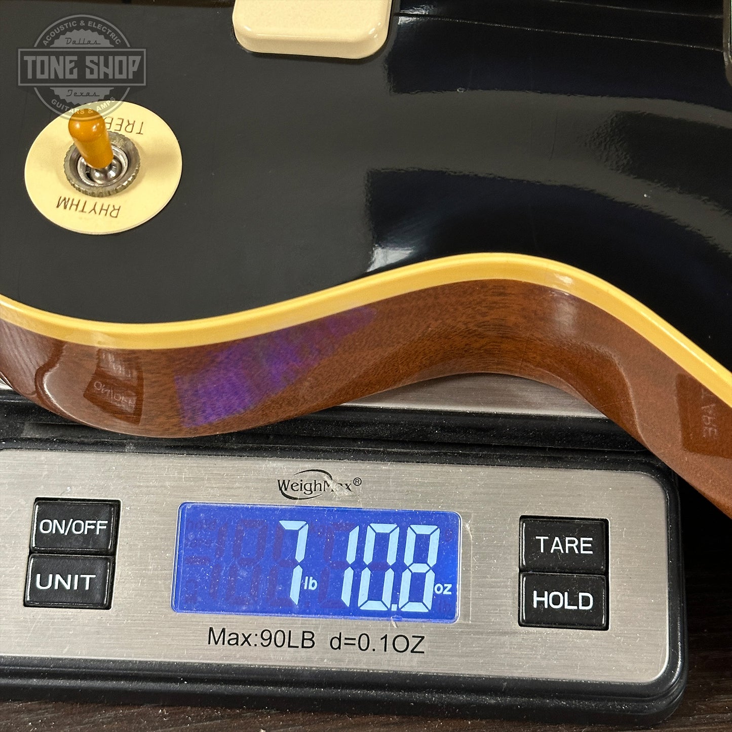 Guitar on a digital scale with 'Tone Shop' branding.