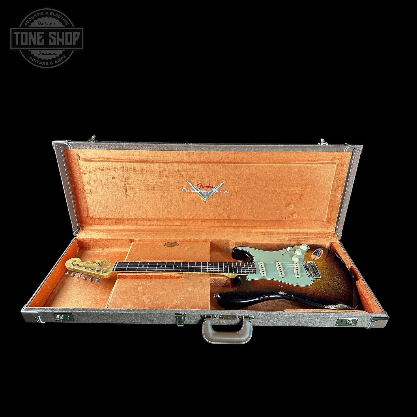 Guitar in an open case with a visible brand logo on a black background