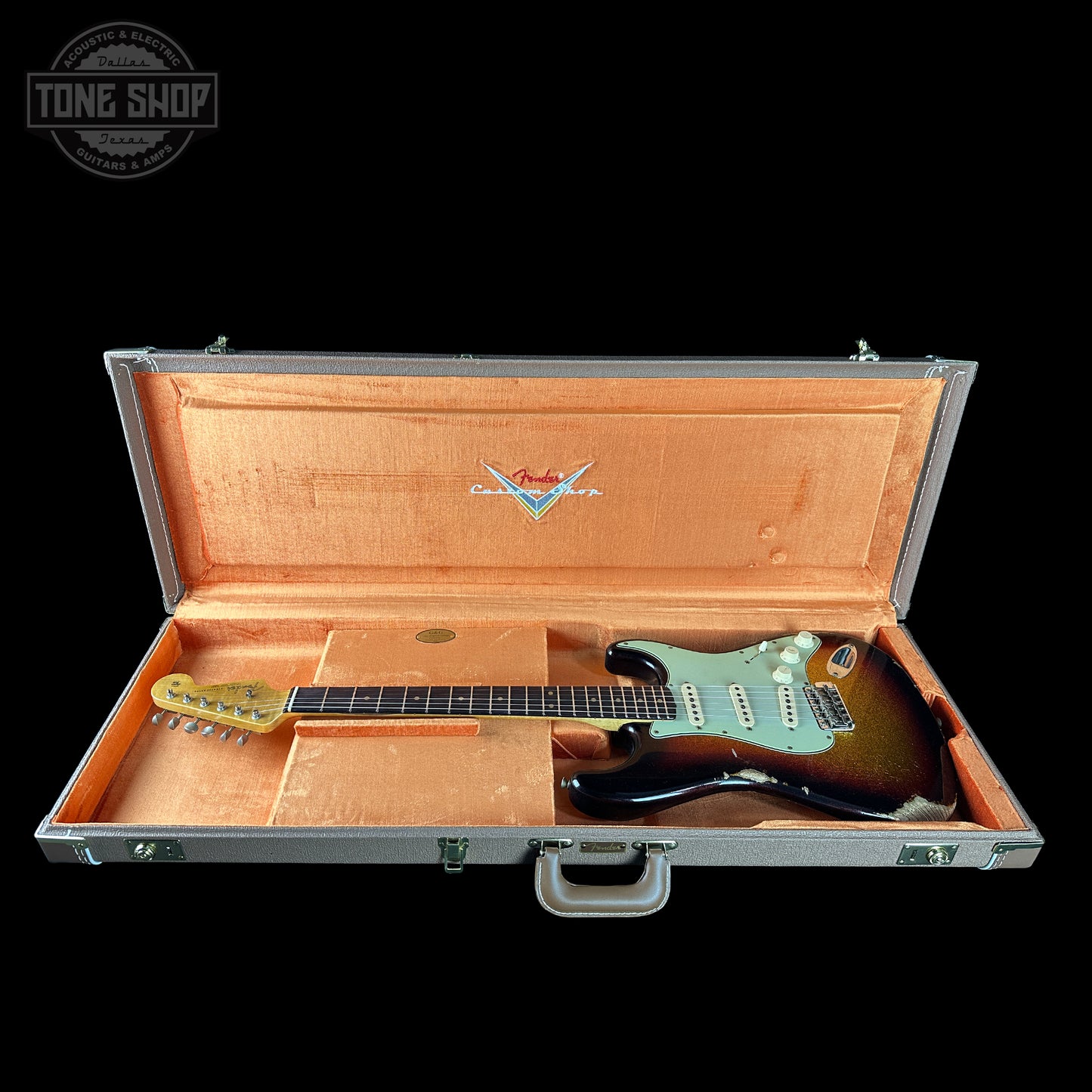 Guitar in an open case with Fender logo on a black background