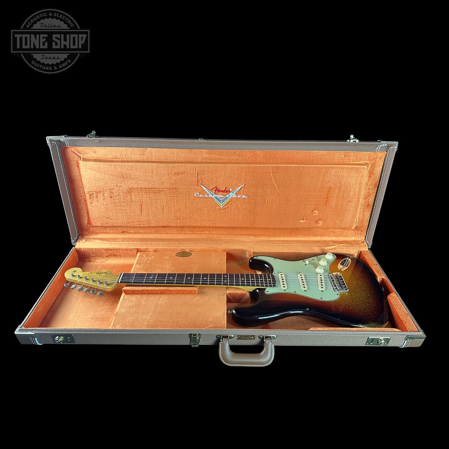 Electric guitar in an open case with a visible brand logo on a black background