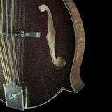Close-up of a Gibson mandolin showing the glossy dark brown glitter finish, f-hole cutout, strings, bridge, and part of the wooden body against a black background.