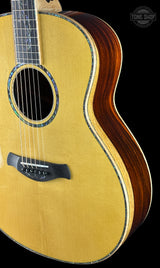 Acoustic guitar with a focus on the body and neck against a black background, featuring the Tone Shop logo.