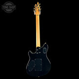 Electric guitar with a black body and wooden neck on a white background, featuring 'Tone Shop' branding.
