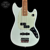 White electric bass guitar with a black pickguard on a black background, featuring the Tone Shop logo.
