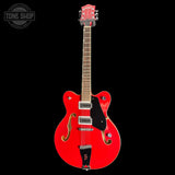 Red electric guitar with a black pickguard on a white background