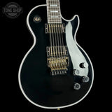 Black electric guitar with a silver pickguard on a black background, featuring the Tone Shop logo.