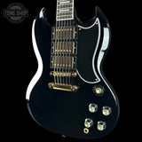 Black electric guitar with gold hardware on a black background, featuring 'Tone Shop' logo.