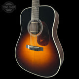 Acoustic guitar with a sunburst finish on a black background, featuring the Tone Shop logo.