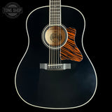 Acoustic guitar with black finish and orange soundhole on a black background, featuring 'Tone Shop' logo.