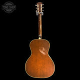 Back view of a wooden acoustic guitar on a black background with 'Tone Shop' logo.