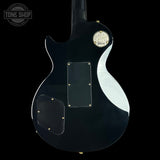 Black electric guitar with a visible Gibson logo on a black background