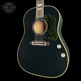 A black acoustic guitar with a glossy finish, cream-colored binding, and a distinctive green-and-black striped pickguard, shown against a solid black background.