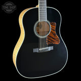 Black acoustic guitar with a wood pattern on a black background, featuring the Tone Shop logo.