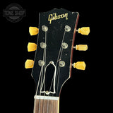 Gibson guitar headstock with yellow tuning pegs on a black background