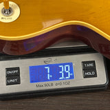Guitar being weighed on a digital scale with a display showing weight.