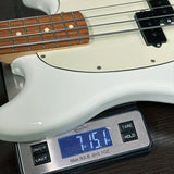 White electric bass guitar on a digital scale displaying weight.