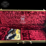 Open Fender 70th Anniversary Elmosphere Special Edition bass case with deep red plush velvet interior, gold-toned exterior shell, and included accessories including a strap and papers.