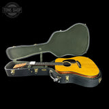 Acoustic guitar in a hard-shell case with 'Tone Shop' logo in the corner.
