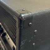 Close-up of a guitar amplifier with a textured surface and visible screws.