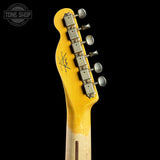 Close-up of the headstock of a yellow electric guitar against a black background, showing six silver tuning pegs and a signature-style logo printed on the back.