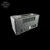 A black textured guitar amplifier head photographed at an angle against a solid black background, with a Tone Shop watermark in the upper left corner.