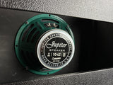 A close-up of a green Jupiter Speaker 8x10-LC ceramic condenser speaker mounted in a black textured panel.