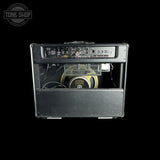 A vintage Fender Jazz Bass amplifier head with its front cover removed, showing the internal speaker and control panel, set against a solid black background.