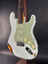 White electric guitar with a black pickguard on a dark background