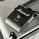 A Marshall Channel guitar effects pedal in black with white script branding, resting on a textured gray surface.