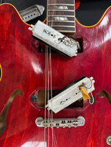 Close-up of a red electric guitar with visible hardware and strings.
