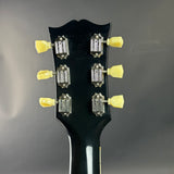 Close-up of a guitar headstock with tuning pegs on a dark background