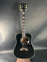 Black acoustic guitar on a reflective gray surface