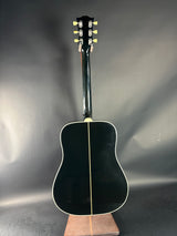 Black acoustic guitar on a reflective gray surface