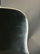 Close-up of a black guitar neck with visible scratches against a dark background