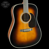 A classic acoustic guitar with a sunburst finish, featuring a dark brown outer edge fading to a warm amber-orange center, set against a solid black background.