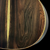 Close-up of a guitar body showing dark brown wood grain with a light tan central inlay stripe and a light-colored edge border against a black background.