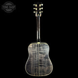 The back of a acoustic guitar with a dark, figured maple top showing prominent grain patterns, a dark neck, and cream-colored tuners, set against a solid black background with a Tone Shop logo in the top left corner.