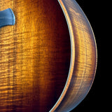 Close-up of a wooden acoustic guitar body showing the rich, warm brown wood grain and a portion of the blue bridge against a solid black background.