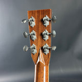 Close-up of a guitar headstock with tuning pegs on a gray background