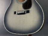 Close-up of an acoustic guitar with a dark gray finish on a dark background