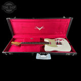 A white electric guitar resting inside an open black hard case with bright pink velvet lining. The case lid has a silver metal logo plate, and a small plastic bag is placed in front of the open case against a solid black background.