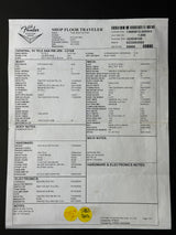 A printed FedEx Shop Floor Traveler manifest form with dense black text, barcodes, and a small yellow circular stamp near the bottom, photographed against a dark background.