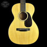 A natural wood acoustic guitar shown from the front against a solid black background, with a Tone Shop watermark in the upper left corner.
