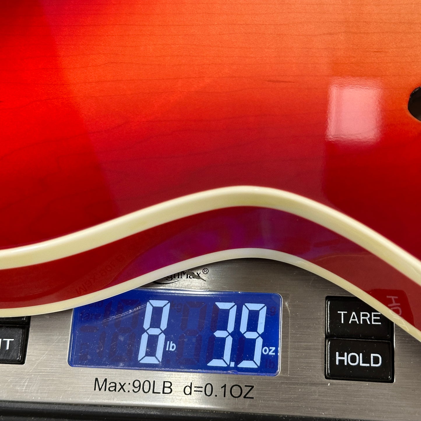Digital scale displaying weight of a red guitar