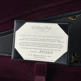 A black leather Martin Custom Shop edition guitar certificate of authenticity card, displayed inside a dark burgundy velvet-lined Martin guitar case.