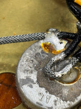 Close-up of a metal component with wires and corrosion on a textured surface