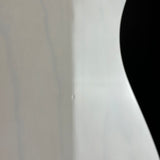 Close-up of a glossy white curved surface with a black shape visible on the right side.