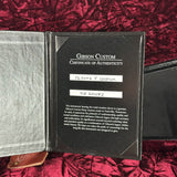 Gibson Custom Certificate of Authenticity on a red textured surface