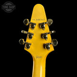 Close-up of a yellow guitar headstock with tuning pegs on a black background, featuring the Gibson logo.