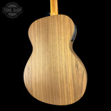 The back of a natural wood acoustic guitar, showing the grain of the soundboard, photographed against a solid black background with a Tone Shop watermark in the top left corner.